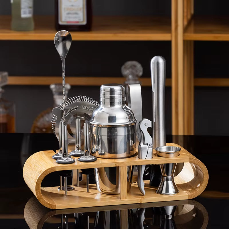 Stainless steel cocktail shaker set with bar tools on a wooden stand.